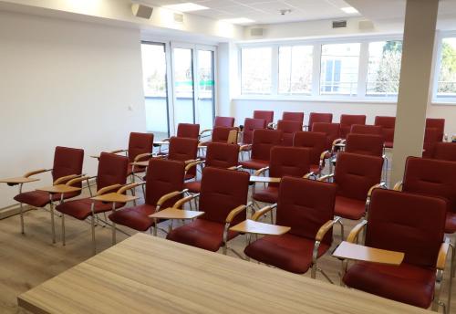 a room with red chairs and tables and windows at Budafoki Sporthotel in Budapest