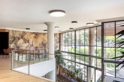 a lobby with a wall of windows and a staircase at Acta Pirámides in Madrid