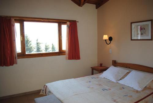 a bedroom with a bed and a large window at Alun Bungalows Apart in San Carlos de Bariloche