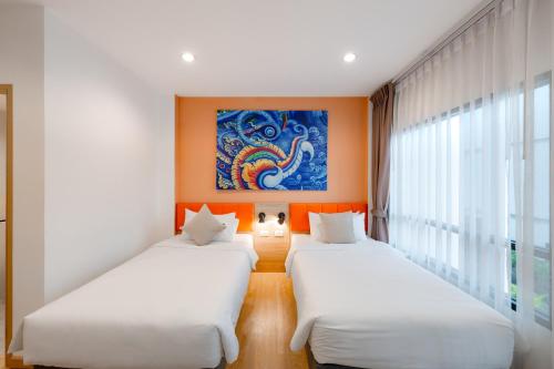 two beds in a room with a painting on the wall at Moji Don Mueang Airport Hotel - Bangkok in Bangkok