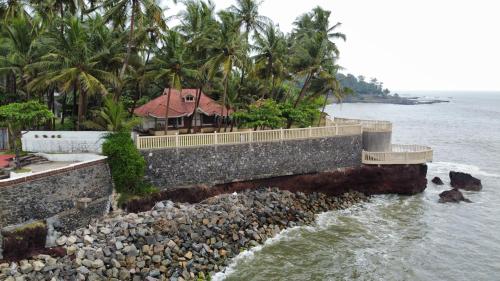 a house on a stone wall next to the water at Willo stays The Metro Landsend Beach Resorts in Kannur