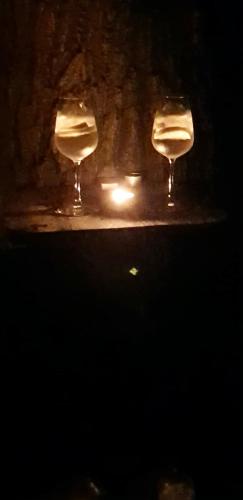 two wine glasses sitting on a table with a candle at Blockhaus Chalet mit beheizbarem Badefass und Infrarotsauna auf der Terrasse in Oberschützen
