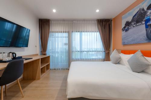 a hotel room with a bed and a desk and a television at Moji Don Mueang Airport Hotel - Bangkok in Bangkok