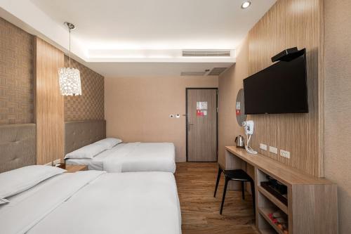 a hotel room with two beds and a flat screen tv at The Riverside Hotel Hengchun in Hengchun