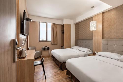 a hotel room with two beds and a television at The Riverside Hotel Hengchun in Hengchun
