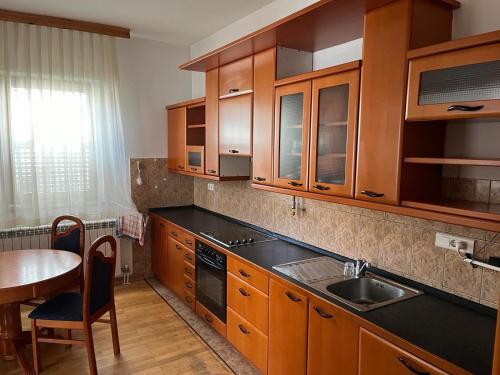 a kitchen with wooden cabinets and a table and a sink at Old Town Villa Sarajevo in Sarajevo