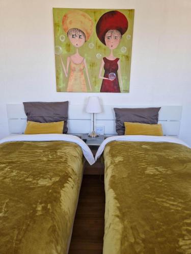 deux lits dans une chambre avec un tableau au mur dans l'établissement Villa Fresquet, à Cherbourg en Cotentin