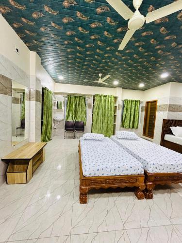 a bedroom with two beds and a ceiling with green curtains at Hotel RPR grand in Narasaraopet