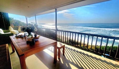 a balcony with a table and a view of the ocean at Copper Beach Villa 2 Umdloti in Umdloti