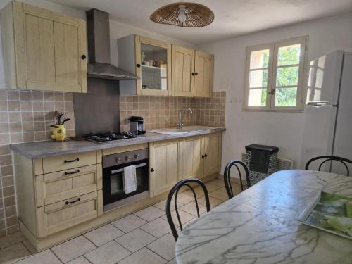 une cuisine avec des placards en bois et une table avec un comptoir dans l'établissement Villa Trempadou, à Gordes