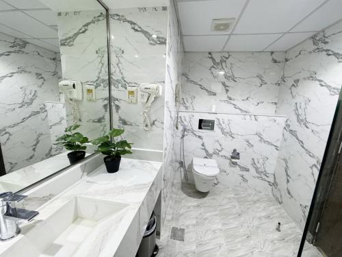 a white bathroom with a sink and a toilet at Fortune Plaza Hotel, Dubai Airport in Dubai