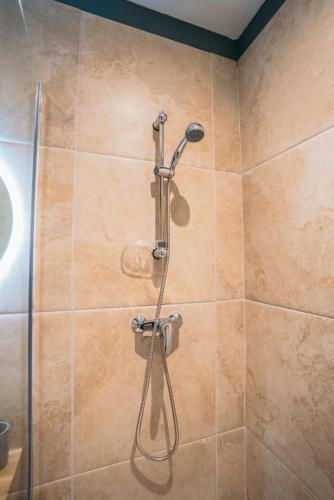 une douche avec pommeau de douche dans une salle de bain dans l'établissement Bel appartement confortable et moderne, à Brignon