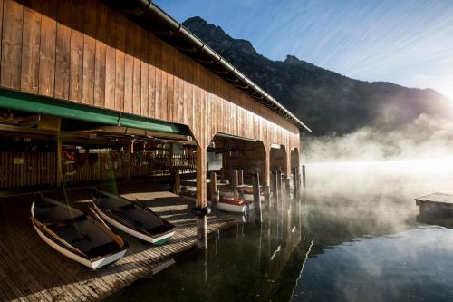 a building with boats sitting on the water next to at Hotel Fischer am See in Heiterwang
