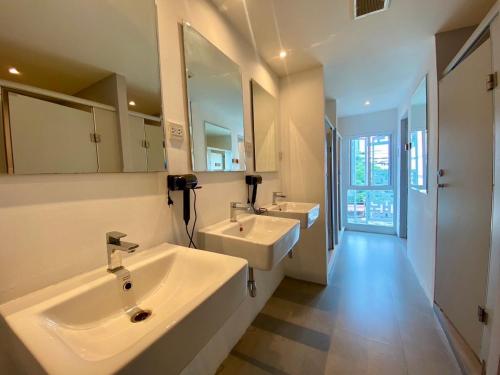 a bathroom with two sinks and two mirrors at The Motuga Hostel Bangkok in Bangkok