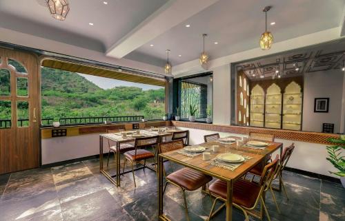 a dining room with tables and chairs and a large window at Artisav House-A Luxury Boutique Stay in Jaipur