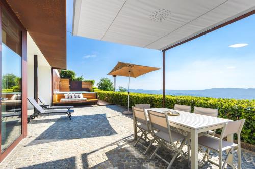 a patio with a table and chairs and an umbrella at Casa sulle Langhe - Luxury Pool, Sauna and Jacuzzi in Diano dʼAlba