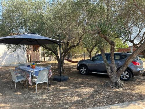 a table and chairs under an umbrella next to a car at ''Mary's House'' Entire residence Olympiada Halkidiki Near to Sea 200m ! in Olympiada