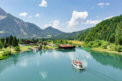 a boat on a river with mountains in the background at Hotel Fischer am See in Heiterwang