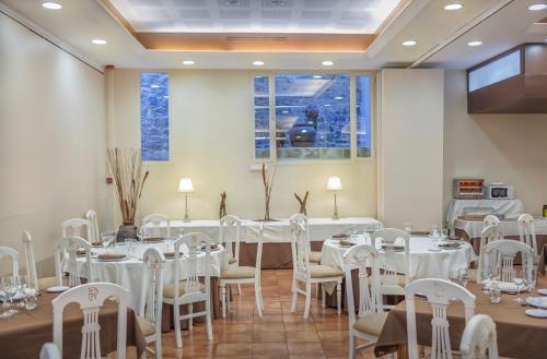 a room with tables and chairs with white tablecloths at Hotel Rosaleda Don Pedro in Úbeda