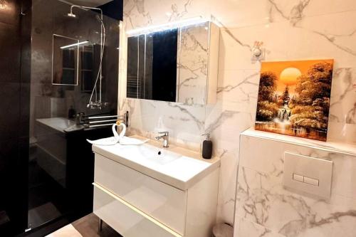 une salle de bain blanche avec un lavabo et un miroir dans l'établissement Parc Luxembourg, à Paris