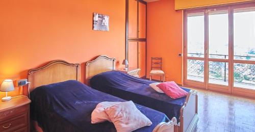 two beds in a room with orange walls at Villa Vera in Verbania
