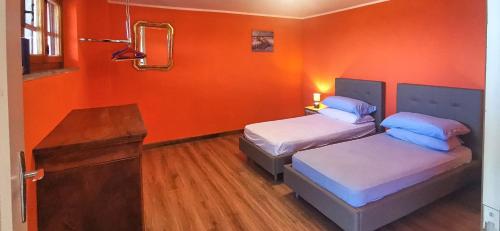 two beds in a room with an orange wall at Villa Vera in Verbania