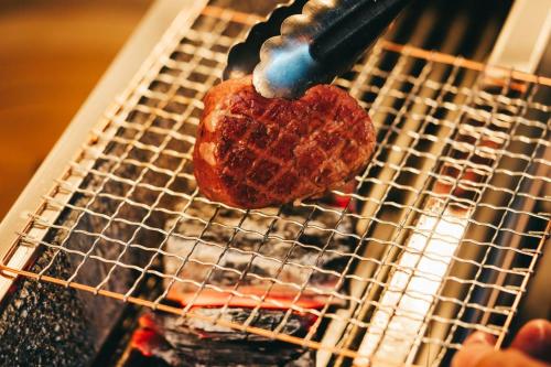 a piece of meat being cooked on a grill at 森のオーベルジュ 三 みつ - 旧 森厚真hotel CHUPKI - in Chitose
