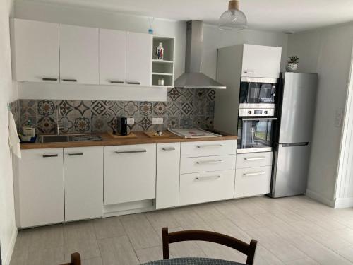une cuisine avec des armoires blanches et un réfrigérateur en acier inoxydable dans l'établissement Ty Ar Pesketour, à Penmarcʼh