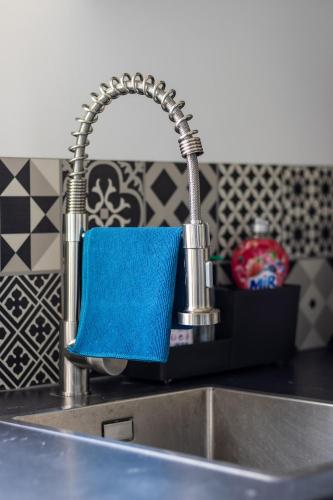 - un évier de cuisine avec un robinet et une éponge bleue dans l'établissement Les Fauvelles Paris La Défense, à Courbevoie
