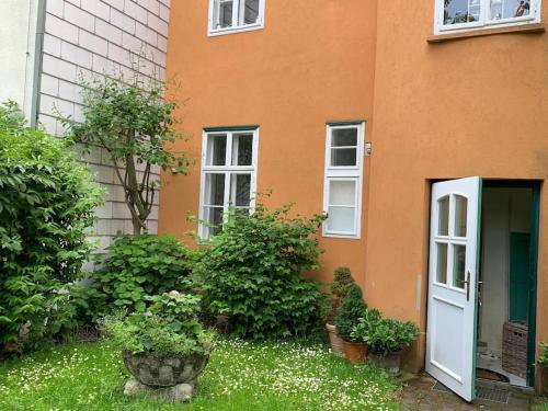 an orange building with a white door and some bushes at Villa guest suite near Vienna in Perchtoldsdorf