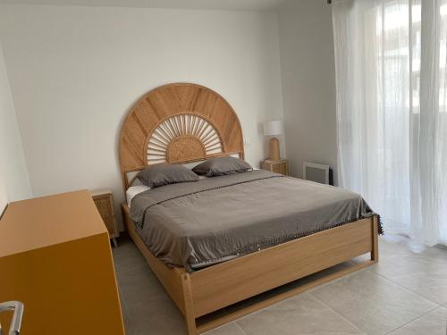 une chambre avec un grand lit avec une tête de lit en bois dans l'établissement TRES BEL F2 NEUF, GRANDE TERRASSE, TRES BIEn SITUE, à Narbonne