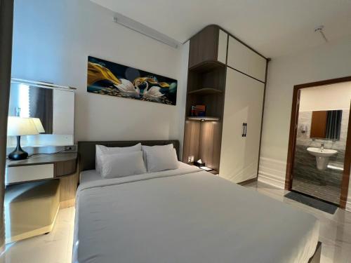 a bedroom with a large white bed and a bathroom at Dan's house in Kinh Dinh