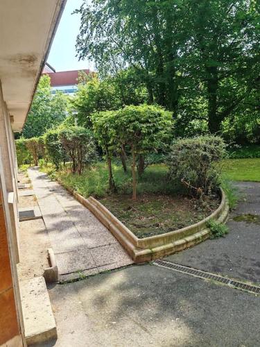 un jardin avec des arbres dans une allée à côté d'une maison dans l'établissement Le Sunshine - 2 people studio & Todler - Cosy - Porte des Lilas, aux Lilas