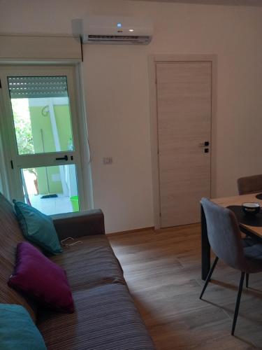 a living room with a couch and a table and a door at Luxury Garden Flat in Carbonia