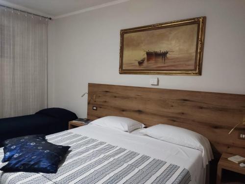 a bedroom with a bed and a picture on the wall at Hotel Signorini in Castiglioncello