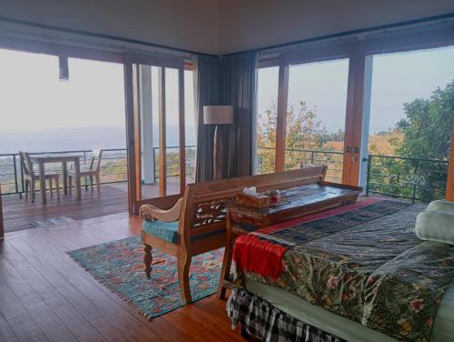 a bedroom with a bed and a chair and windows at Liri Villa - 4 BRs - Ocean, Valley view in Temukus