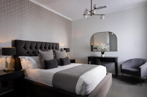 a bedroom with a bed and a chair and a mirror at Palm House Boutique Hotel and Spa in Cape Town