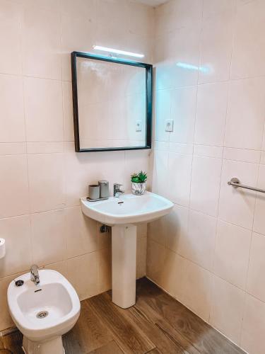 a bathroom with a sink and a toilet and a mirror at Pitayas Apartment in Corralejo