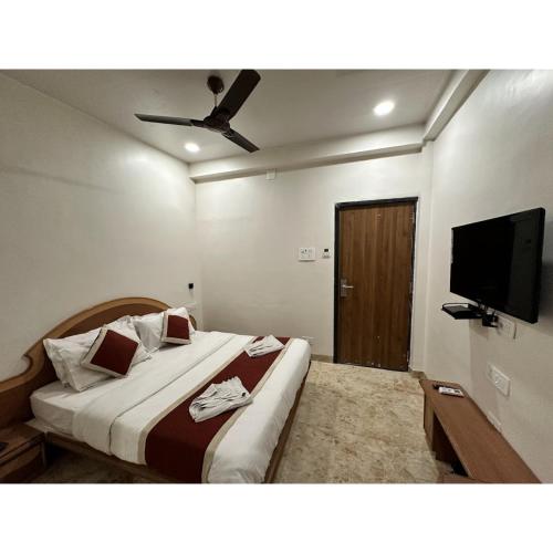 a bedroom with a large bed and a flat screen tv at Hotel Always Welcome by SAH in Mount Ābu