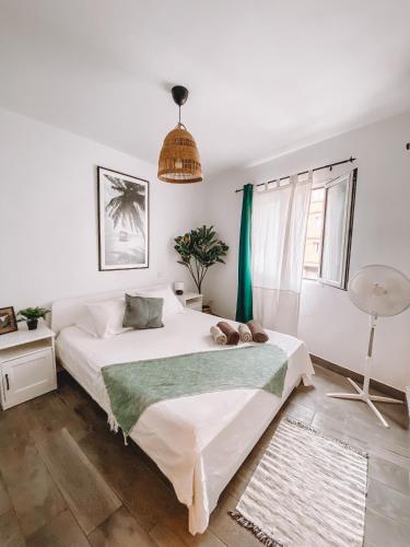 a bedroom with a large white bed and a window at Pitayas Apartment in Corralejo