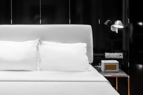 a white bed with a clock on a side table at Browns Downtown Hotel in Lisbon