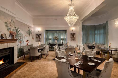 a dining room with tables and chairs and a fireplace at Palm House Boutique Hotel and Spa in Cape Town