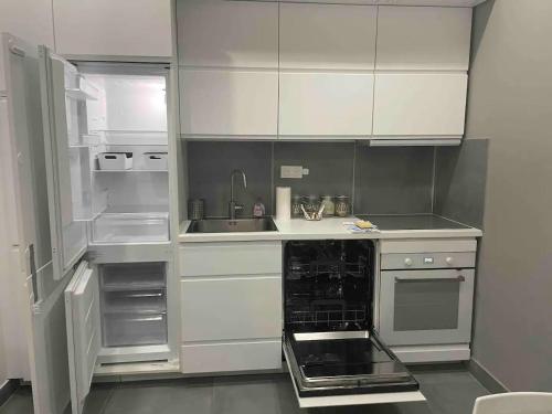 La cuisine est équipée de placards blancs et d'un réfrigérateur ouvert. dans l'établissement Duplex au Sentier secret au cœur de Paris, à Paris