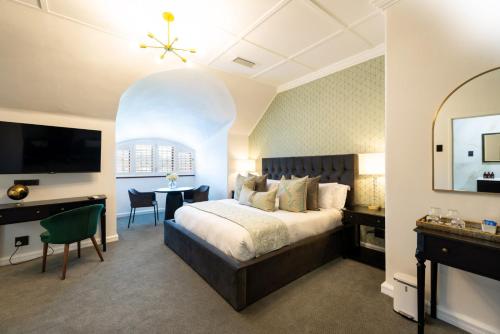 a bedroom with a bed and a desk and a television at Palm House Boutique Hotel and Spa in Cape Town