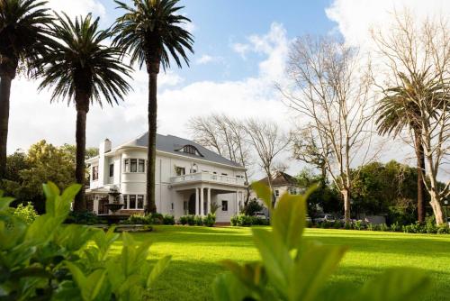 a white house with palm trees in the yard at Palm House Boutique Hotel and Spa in Cape Town