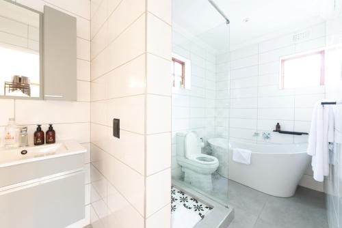 a white bathroom with a tub and a toilet at Palm House Boutique Hotel and Spa in Cape Town