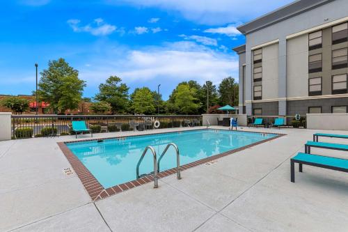 a swimming pool with a bench next to a building at Hampton Inn Florence Midtown near University of North Alabama in Florence