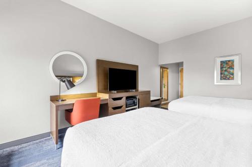 a hotel room with two beds and a desk with a television at Hampton Inn Florence Midtown near University of North Alabama in Florence