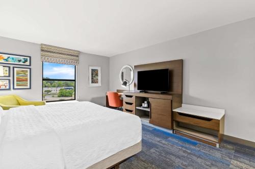 a hotel room with a bed and a desk and a television at Hampton Inn Florence Midtown near University of North Alabama in Florence