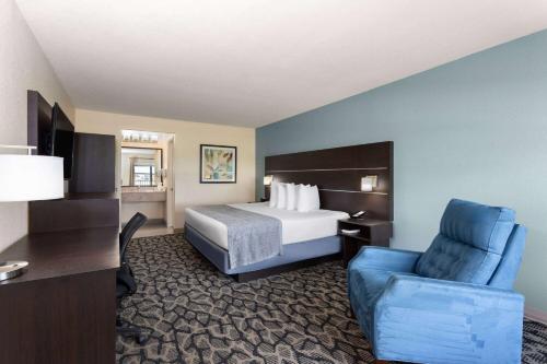 a hotel room with a bed and a blue chair at Baymont by Wyndham Punta Gorda/Port Charlotte in Punta Gorda